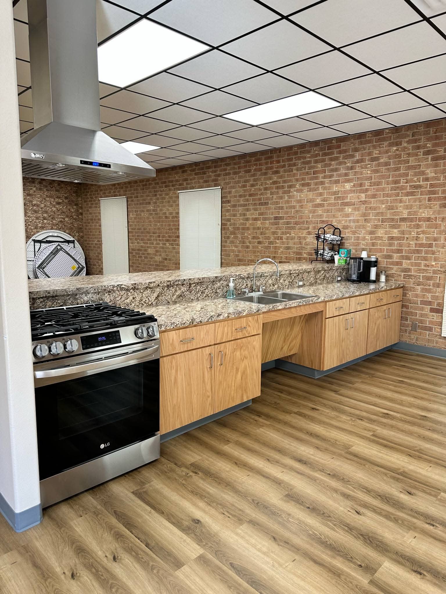 Senior Center kitchen with stove, granite countertops, and wood cabinetry